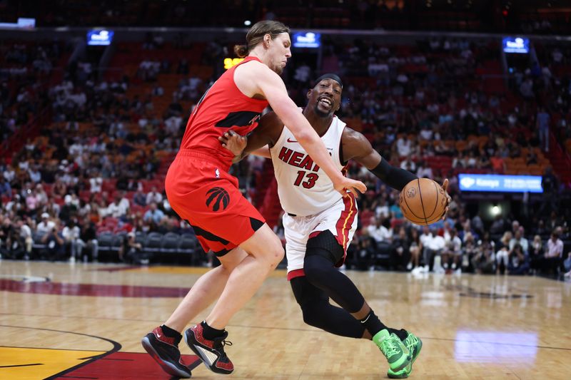 MIAMI, FLORIDA - APRIL 12: Bam Adebayo #13 of the Miami Heat drives against Kelly Olynyk #41 of the Toronto Raptors during the first quarter of the game at Kaseya Center on April 12, 2024 in Miami, Florida. NOTE TO USER: User expressly acknowledges and agrees that, by downloading and or using this photograph, User is consenting to the terms and conditions of the Getty Images License Agreement. (Photo by Megan Briggs/Getty Images)