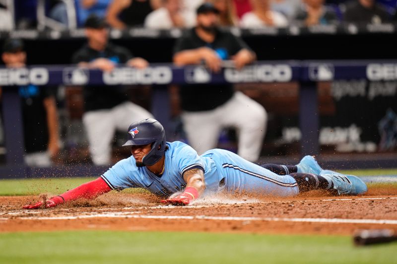 Jun 20, 2023; Miami, Florida, USA; Toronto Blue Jays second baseman Santiago Espinal (5) slides into home base against the Miami Marlins during the eighth inning at loanDepot Park. Mandatory Credit: Rich Storry-USA TODAY Sports