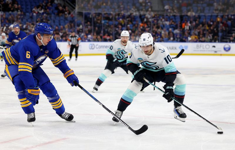 Jan 9, 2024; Buffalo, New York, USA;  Seattle Kraken center Matty Beniers (10) skates with the puck as Buffalo Sabres defenseman Erik Johnson (6) defends during the third period at KeyBank Center. Mandatory Credit: Timothy T. Ludwig-USA TODAY Sports