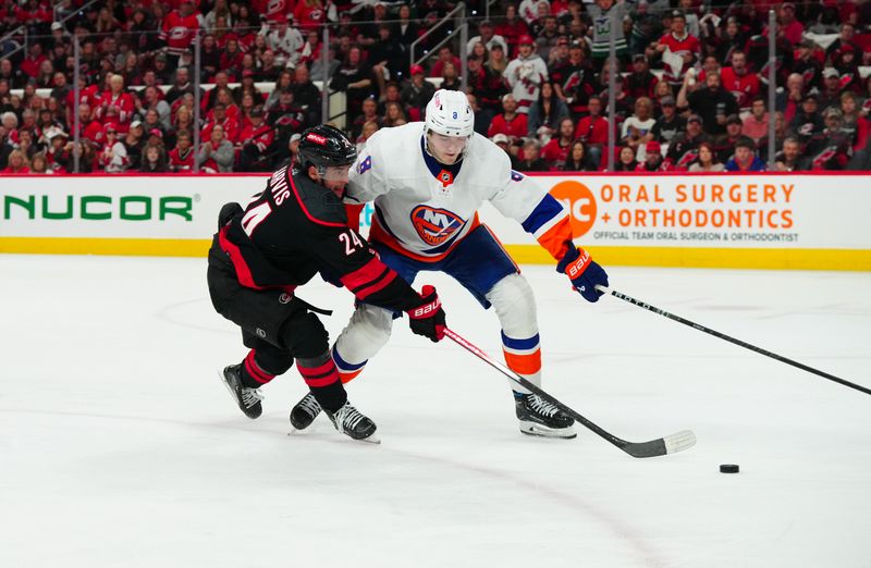 Apr 20, 2024; Raleigh, North Carolina, USA; Carolina Hurricanes center Seth Jarvis (24) gets the shot away past New York Islanders defenseman Noah Dobson (8) during the third period in game one of the first round of the 2024 Stanley Cup Playoffs at PNC Arena. Mandatory Credit: James Guillory-USA TODAY Sports