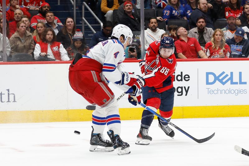 Oct 29, 2024; Washington, District of Columbia, USA; Washington Capitals left wing Andrew Mangiapane (88) shoots the puck as New York Rangers defenseman Braden Schneider (4) defends in the third period at Capital One Arena. Mandatory Credit: Geoff Burke-Imagn Images