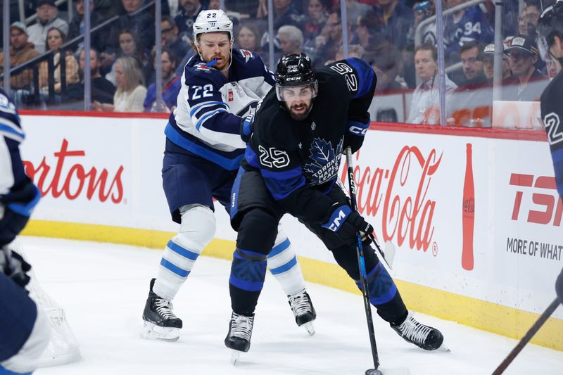 Oct 28, 2024; Winnipeg, Manitoba, CAN;  Toronto Maple Leafs defenseman Connor Timmins (25) tries to skate away from Winnipeg Jets forward Mason Appleton (22) during the second period at Canada Life Centre. Mandatory Credit: Terrence Lee-Imagn Images