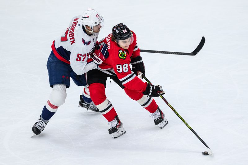 Dec 10, 2023; Chicago, Illinois, USA; Chicago Blackhawks center Connor Bedard (98) plays the puck as Washington Capitals defenseman Trevor van Riemsdyk (57) defends during the third period at the United Center. Mandatory Credit: Daniel Bartel-USA TODAY Sports