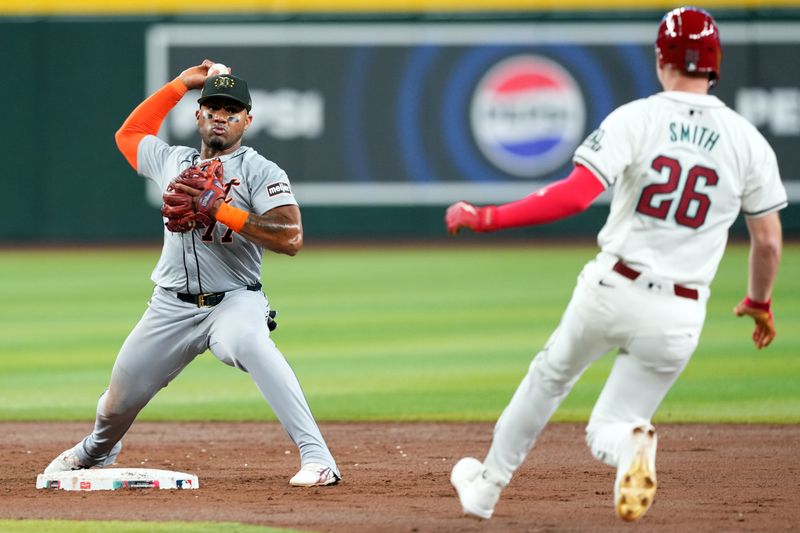 May 19, 2024; Phoenix, Arizona, USA; Detroit Tigers second base Andy Ibáñez (77) throws to first base after forcing out Arizona Diamondbacks outfielder Pavin Smith (26) at second base during the fourth inning at Chase Field. Mandatory Credit: Joe Camporeale-USA TODAY Sports