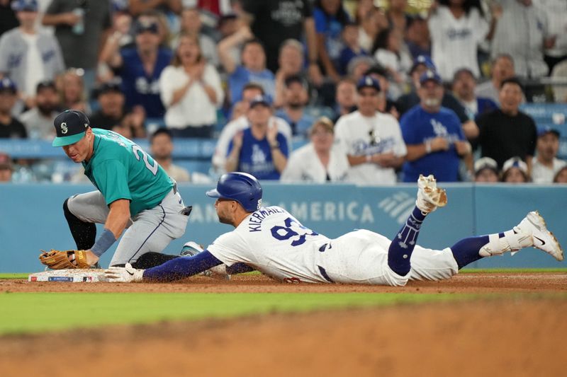 Aug 21, 2024; Los Angeles, California, USA; Los Angeles Dodgers center fielder Kevin Kiermaier (93) slides into third base beneath the tag of Seattle Mariners shortstop Dylan Moore (25) on a triple in the sixth inning at Dodger Stadium. Mandatory Credit: Kirby Lee-USA TODAY Sports