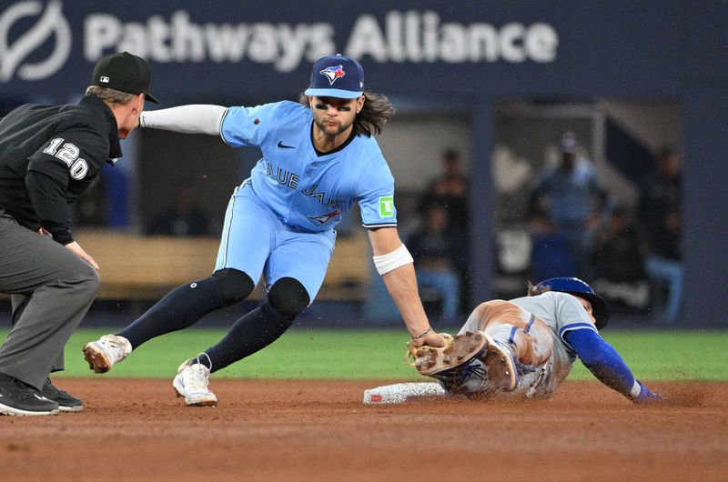Apr 30, 2024; Toronto, Ontario, CAN;   Toronto Blue Jays shortstop Bo Bichette (11) tags out Kansas City Royals shortstop Bobby Witt Jr. (7) on an attempted steal in the sixth inning at Rogers Centre. Mandatory Credit: Dan Hamilton-USA TODAY Sports