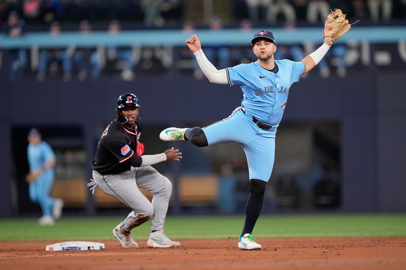 May 4, 2025; Toronto, Ontario, CAN; Toronto Blue Jays shortstop Bo Bichette (11) and Cleveland Guardians center fielder Angel Martinez (1) watch the play at first base after the force out at second base during the third inning at Rogers Centre. Mandatory Credit: John E. Sokolowski-Imagn Images