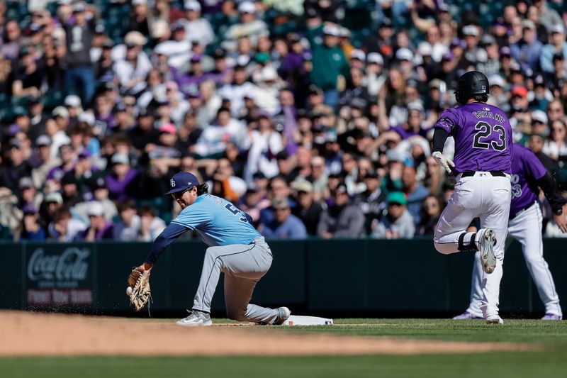 Apr 7, 2024; Denver, Colorado, USA; Tampa Bay Rays first baseman Austin Shenton (54) fields a throw for an out ahead of Colorado Rockies designated hitter Kris Bryant (23) in the eighth inning at Coors Field. Mandatory Credit: Isaiah J. Downing-USA TODAY Sports