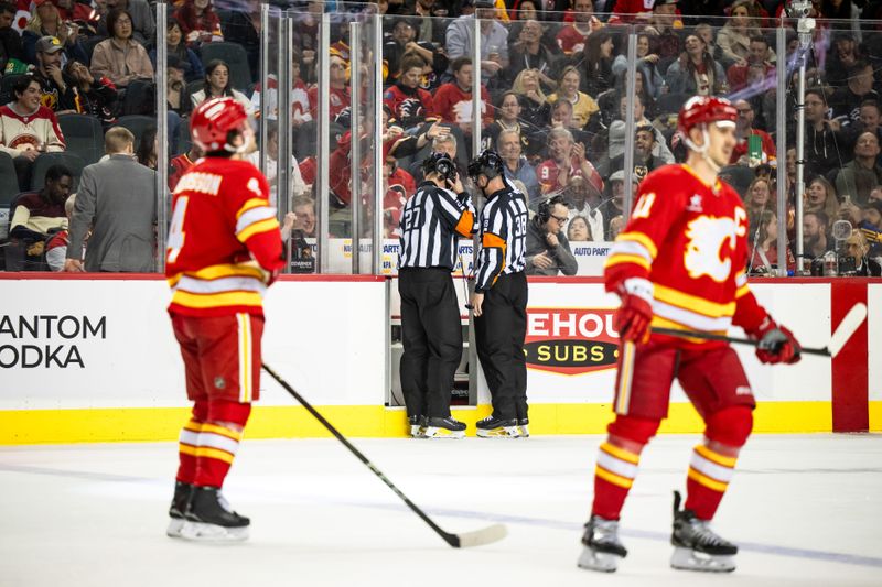 Apr 5, 2025; Calgary, Alberta, CAN; Referees review a potential goal by the Calgary Flames against the Vegas Golden Knights during the second period at Scotiabank Saddledome. Mandatory Credit: Brett Holmes-Imagn Images
