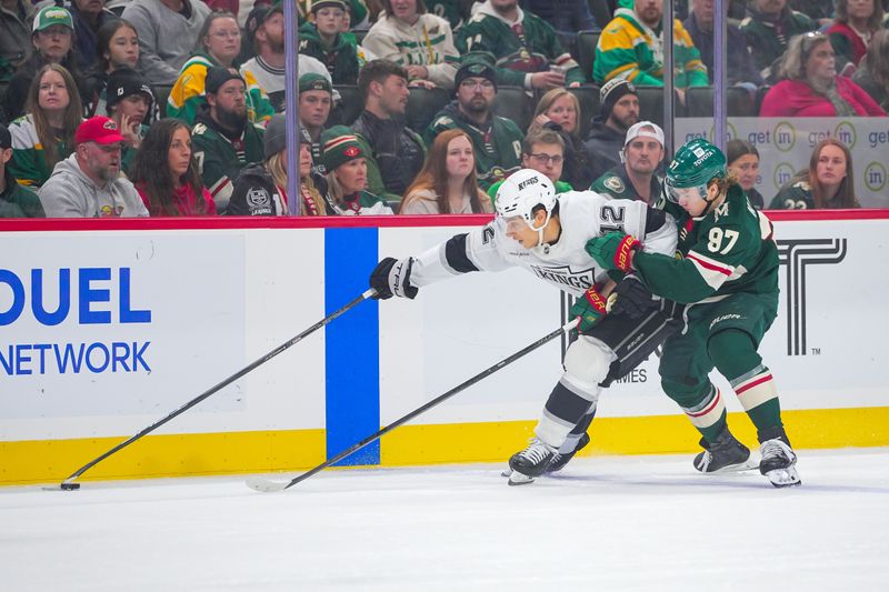 Nov 5, 2024; Saint Paul, Minnesota, USA; Los Angeles Kings left wing Trevor Moore (12) skates with the puck against the Minnesota Wild left wing Kirill Kaprizov (97) in the first period at Xcel Energy Center. Mandatory Credit: Brad Rempel-Imagn Images