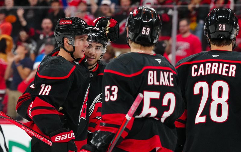 Oct 31, 2024; Raleigh, North Carolina, USA;  Carolina Hurricanes defenseman Sean Walker (26) is congratulated by center Jack Drury (18) and right wing Jackson Blake (53) after his goal against the Boston Bruins during the third period at Lenovo Center. Mandatory Credit: James Guillory-Imagn Images