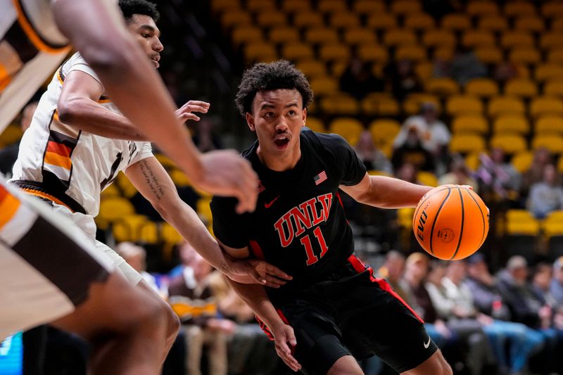 Feb 27, 2024; Laramie, Wyoming, USA; UNLV Runnin' Rebels guard Dedan Thomas Jr. (11) drives against Wyoming Cowboys guard Kael Combs (11) during the second half at Arena-Auditorium. Mandatory Credit: Troy Babbitt-USA TODAY Sports