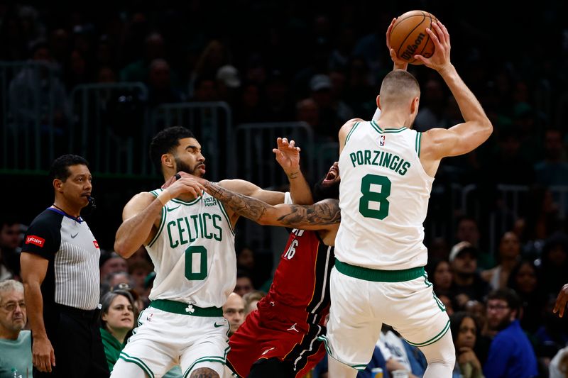 BOSTON, MA - APRIL 21: Caleb Martin #16 of the Miami Heat runs into Kristaps Porzingis #8 of the Boston Celtics as he tries to keep Jayson Tatum #0 from the ball during the first quarter of game one of the Eastern Conference First Round Playoffs at TD Garden on April 21, 2024 in Boston, Massachusetts. NOTE TO USER: User expressly acknowledges and agrees that, by downloading and/or using this Photograph, user is consenting to the terms and conditions of the Getty Images License Agreement. (Photo By Winslow Townson/Getty Images)