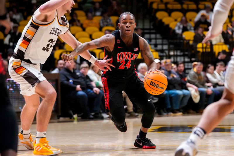 Feb 27, 2024; Laramie, Wyoming, USA; UNLV Runnin' Rebels guard Jackie Johnson III (24) drives against Wyoming Cowboys forward Mason Walters (33) during the second half at Arena-Auditorium. Mandatory Credit: Troy Babbitt-USA TODAY Sports