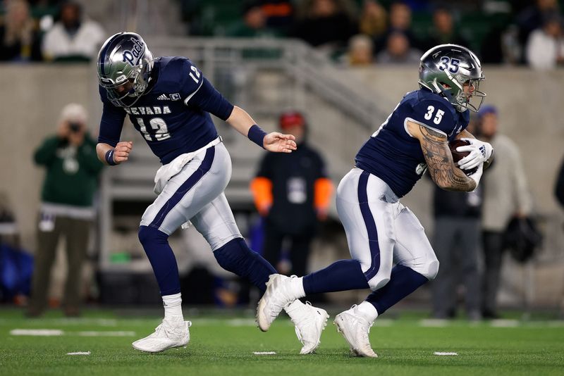 Nov 27, 2021; Fort Collins, Colorado, USA; Nevada Wolf Pack quarterback Carson Strong (12) hands the ball off to running back Toa Taua (35) in the first quarter against the Colorado State Rams at Sonny Lubrick Field at Canvas Stadium. Mandatory Credit: Isaiah J. Downing-USA TODAY Sports