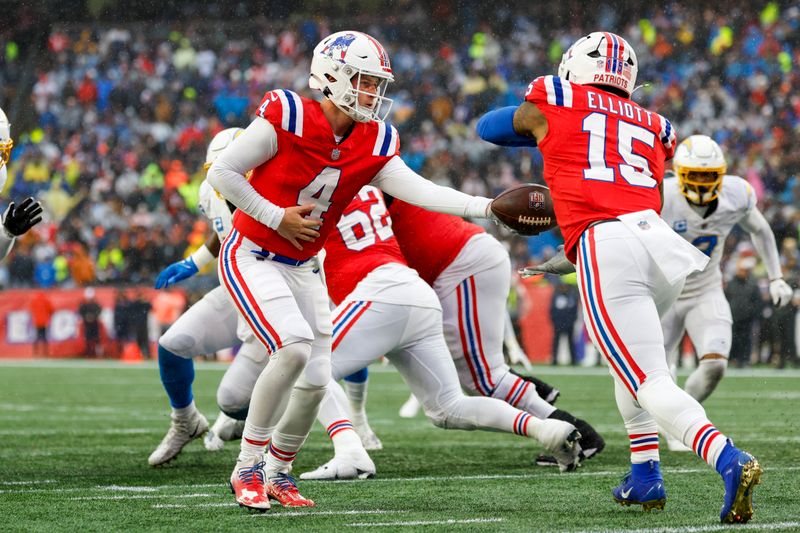 New England Patriots quarterback Bailey Zappe (4) hands off the ball to running back Ezekiel Elliott (15) during the first half of an NFL football game against the Los Angeles Chargers on Sunday, Dec. 3, 2023, in Foxborough, Mass. (AP Photo/Greg M. Cooper)