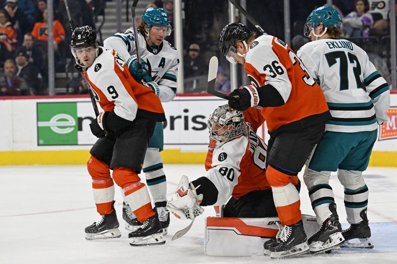 Dec 9, 2025; Philadelphia, Pennsylvania, USA; Philadelphia Flyers goaltender Dan Vladar (80) covers the puck with help from defenseman Jamie Drysdale (9) and defenseman Emil Andrae (36) against the San Jose Sharks during the second period at Xfinity Mobile Arena. Mandatory Credit: Eric Hartline-Imagn Images