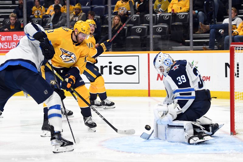 Nov 26, 2023; Nashville, Tennessee, USA; Winnipeg Jets goaltender Laurent Brossoit (39) makes a save on a shot by Nashville Predators center Yakov Trenin (13) during the third period at Bridgestone Arena. Mandatory Credit: Christopher Hanewinckel-USA TODAY Sports