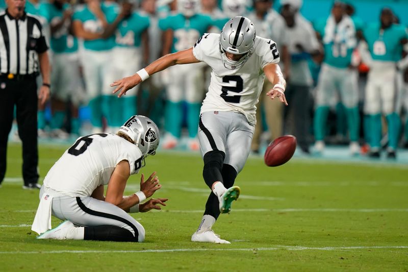 Las Vegas Raiders place kicker Daniel Carlson (2) kicks a field goal as punter AJ Cole (6) holds, during the second half of a NFL preseason football game against the Miami Dolphins, Saturday, August 20, 2022, in Miami Gardens, Fla. (AP Photo/Wilfredo Lee)