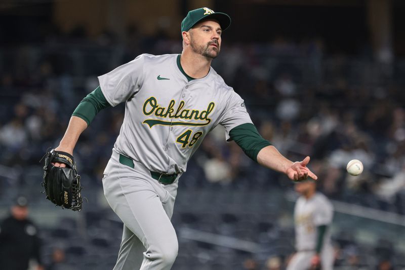 Apr 23, 2024; Bronx, New York, USA; Oakland Athletics relief pitcher T.J. McFarland (48) tosses the ball to first base for an out during the seventh inning against the New York Yankees at Yankee Stadium. Mandatory Credit: Vincent Carchietta-USA TODAY Sports