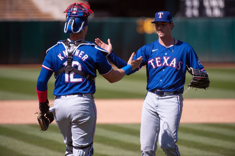 May 7, 2024; Oakland, California, USA; Texas Rangers catcher Andrew Knizner (12) and pitcher Cole Winn (60) celebrate after defeating the Oakland Athletics at Oakland-Alameda County Coliseum. Mandatory Credit: Ed Szczepanski-USA TODAY Sports