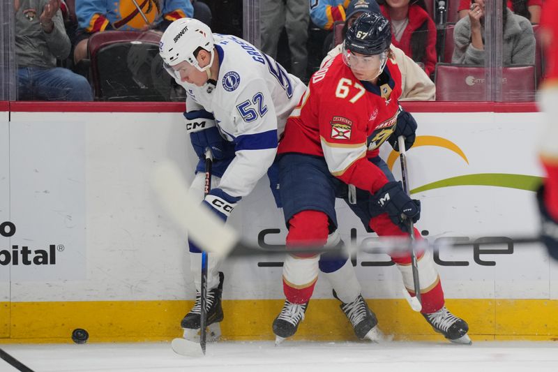 Sep 30, 2024; Sunrise, Florida, USA; Tampa Bay Lightning right wing Maxim Groshev (52) and Florida Panthers right wing William Lockwood (67) battle for possession during the first period at Amerant Bank Arena. Mandatory Credit: Jim Rassol-Imagn Images