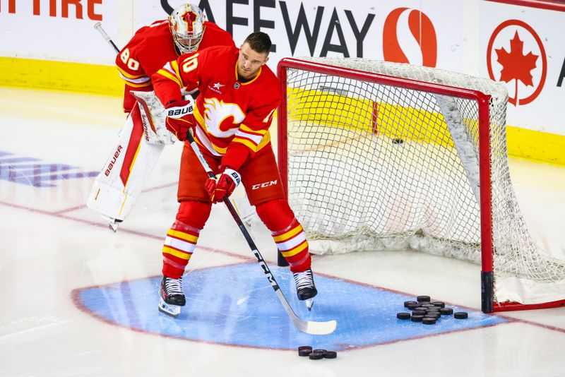 Oct 4, 2024; Calgary, Alberta, CAN; Calgary Flames center Jonathan Huberdeau (10) passes the pucks during the warmup period against the Winnipeg Jets at Scotiabank Saddledome. Mandatory Credit: Sergei Belski-Imagn Images