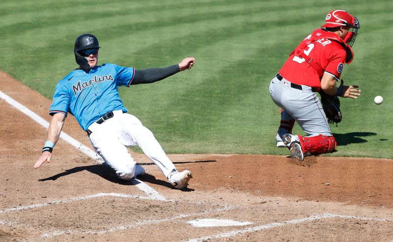 Feb 25, 2025; Jupiter, Florida, USA;  Miami Marlins right fielder Griffin Conine (18) scores against Washington Nationals catcher Andrew Knizner (9) during the fourth inning at Roger Dean Chevrolet Stadium. Mandatory Credit: Rhona Wise-Imagn Image 