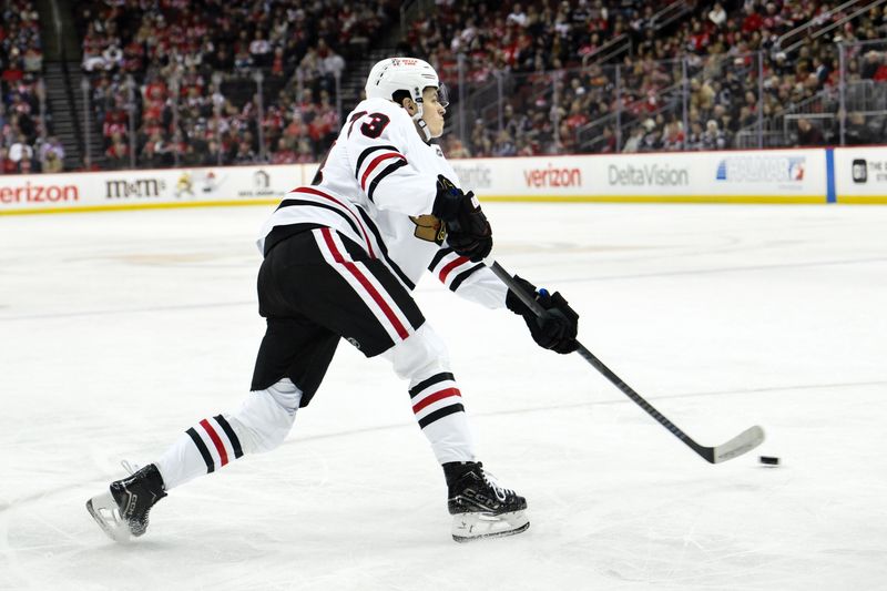 Dec 14, 2024; Newark, New Jersey, USA; Chicago Blackhawks left wing Lukas Reichel (73) shoots the puck against the New Jersey Devils during the first period at Prudential Center. Mandatory Credit: John Jones-Imagn Images