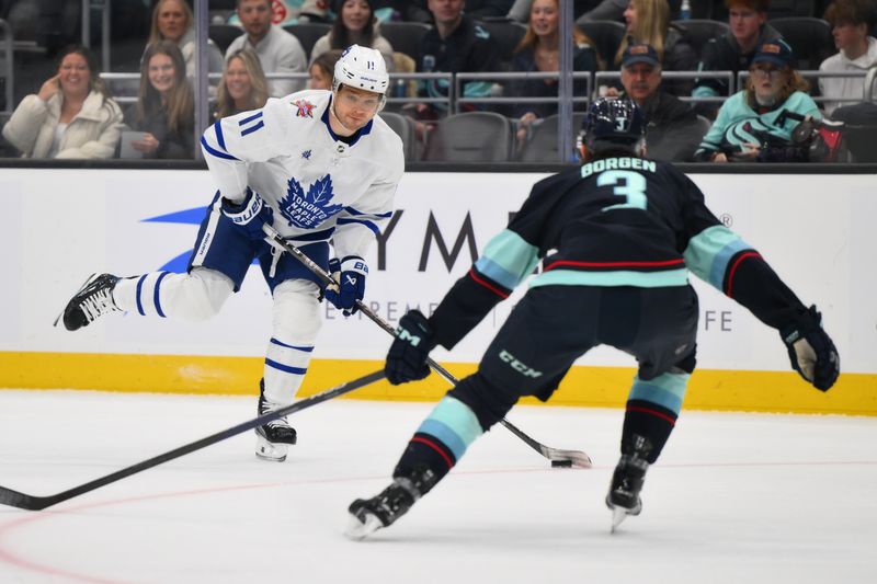 Jan 21, 2024; Seattle, Washington, USA; Toronto Maple Leafs center Max Domi (11) passes the puck while defended by Seattle Kraken defenseman Will Borgen (3) during the first period at Climate Pledge Arena. Mandatory Credit: Steven Bisig-USA TODAY Sports