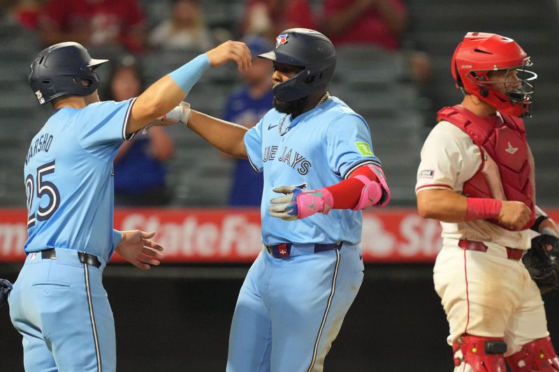 Aug 14, 2024; Anaheim, California, USA; Toronto Blue Jays first baseman Vladimir Guerrero Jr. (27) celebrates with left fielder Daulton Varsho (25) after hitting a two-run home run in the eighth inning as Los Angeles Angels catcher Matt Thaiss (21) watches at Angel Stadium. Mandatory Credit: Kirby Lee-USA TODAY Sports