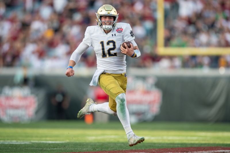 Dec 30, 2022; Jacksonville, FL, USA; Notre Dame Fighting Irish quarterback Tyler Buchner (12) runs for a touchdown against the South Carolina Gamecocks in the second quarter in the 2022 Gator Bowl at TIAA Bank Field. Mandatory Credit: Jeremy Reper-USA TODAY Sports