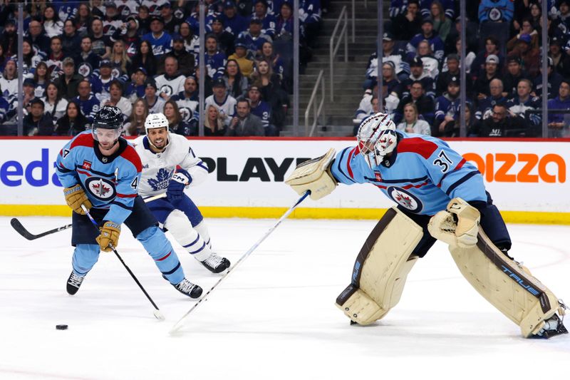 Jan 27, 2024; Winnipeg, Manitoba, CAN; Winnipeg Jets goaltender Connor Hellebuyck (37) pokes the puck to Winnipeg Jets defenseman Josh Morrissey (44) chased by Toronto Maple Leafs right wing Ryan Reaves (75) in the first period at Canada Life Centre. Mandatory Credit: James Carey Lauder-USA TODAY Sports