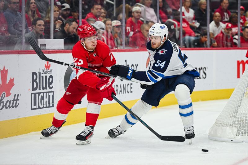 Oct 30, 2024; Detroit, Michigan, USA; Detroit Red Wings left wing Lucas Raymond (23) passes the puck as Winnipeg Jets defenseman Dylan Samberg (54) defends during the second period at Little Caesars Arena. Mandatory Credit: Tim Fuller-Imagn Images