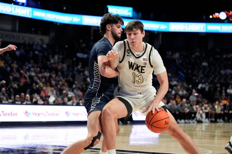 Dec 14, 2025; Winston-Salem, North Carolina, USA;  Wake Forest Demon Deacons forward Cooper Schwieger (13) goes to the basket defended by Queens University Royals guard Yoav Berman (24) during the first half at Lawrence Joel Veterans Memorial Coliseum. Mandatory Credit: Jim Dedmon-Imagn Images