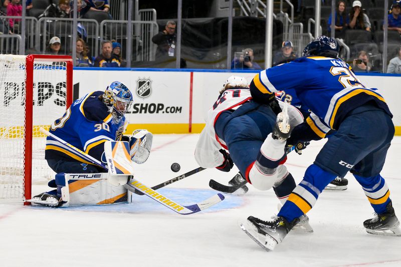 Oct 1, 2024; St. Louis, Missouri, USA;  St. Louis Blues goaltender Joel Hofer (30) and center Jordan Kyrou (25) defend the net against Columbus Blue Jackets defenseman Stanislav Svozil (81) during the first period at Enterprise Center. Mandatory Credit: Jeff Curry-Imagn Images