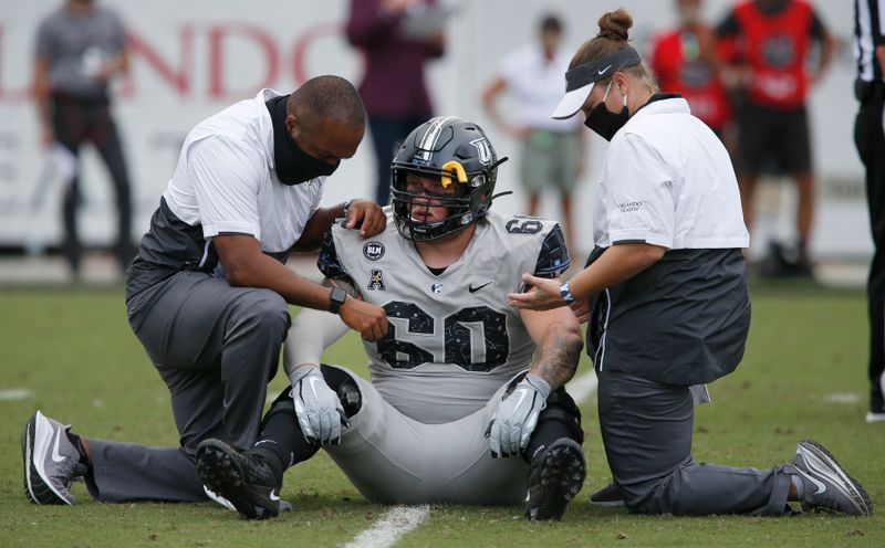 Oct 24, 2020; Orlando, Florida, USA; UCF Knights offensive lineman Josh McMullen (60) is attended to by trainers during the first quarter against the Tulane Green Wave at the  Bounce House. Mandatory Credit: Reinhold Matay-USA TODAY Sports