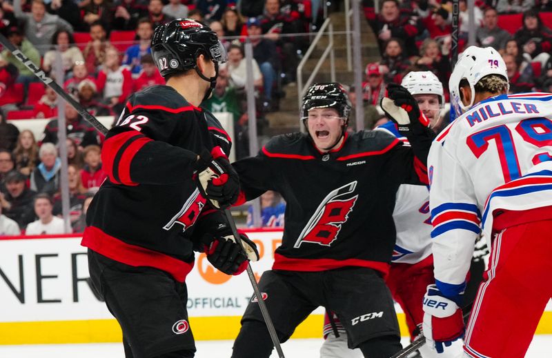 Nov 27, 2024; Raleigh, North Carolina, USA;  Carolina Hurricanes center Jesperi Kotkaniemi (82) is congratulated by left wing Eric Robinson (50) after his goal against New York Rangers goaltender Igor Shesterkin (31) and defenseman K'Andre Miller (79) during the third period at Lenovo Center. Mandatory Credit: James Guillory-Imagn Images